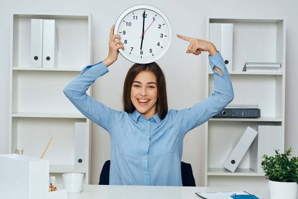 Νεαρή όμορφη επιχειρηματίας στο γραφείο δείχνει το ρολόι  - Φωτογραφία, εικόνα
