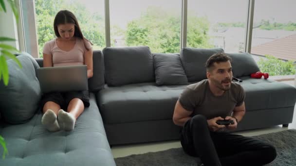 Les couples, les jeunes femmes, insatisfaits de l'homme jouant à des jeux bruyants, la distrayant du travail à la maison, dans une situation épidémique provoquant un travail à la maison pour Distanciation sociale - Séquence, vidéo