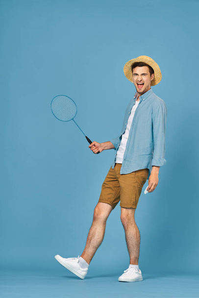 Young man playing tennis isolated on blue background, studio shot - Foto, imagen
