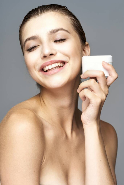 Studio shot of young beautiful woman with cream, beauty product on an isolated background - Φωτογραφία, εικόνα