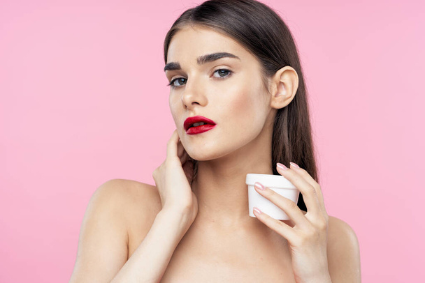Cuidado de la piel y belleza. Retrato de joven hermosa mujer con crema sobre fondo rosa
 - Foto, Imagen