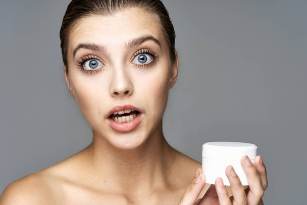 Студийный снимок молодой красивой женщины со сливками, косметический продукт на изолированном фоне
 - Фото, изображение