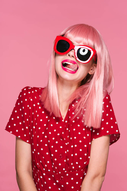молодая красивая женщина в розовом парике и солнцезащитных очках позирует в студии
  - Фото, изображение