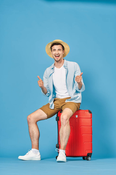 Νεαρός με κόκκινη βαλίτσα στο στούντιο - Φωτογραφία, εικόνα