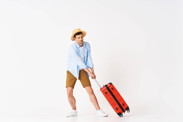 Young man with red suitcase in studio - Foto, Imagen