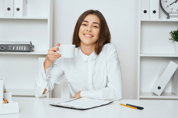 Молодая красивая деловая женщина с чашкой кофе в офисе  - Фото, изображение
