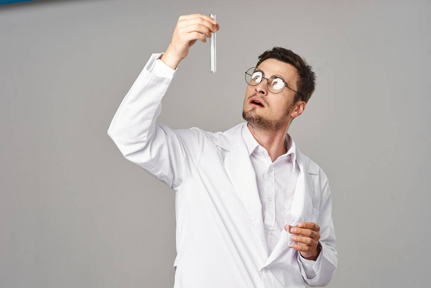 Doctor looking at  test tube on grey background. Studio shot - Foto, Imagen