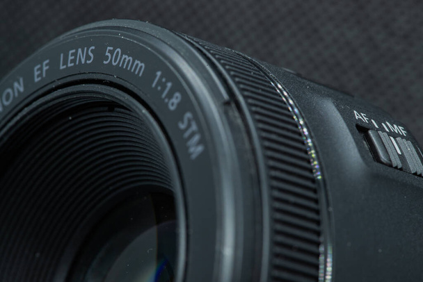 Foto de primer plano macro de la lente a la cámara réflex digital en la vista frontal de fondo oscuro con rango focal y descripción de la aputura
. - Foto, imagen