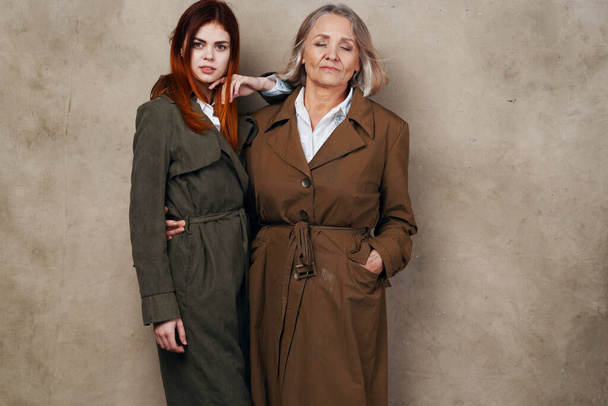 young woman with her mother   in coats posing in studio    - Photo, Image