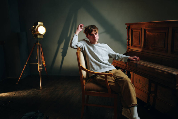young handsomen man posing in studio near piano                               - Foto, imagen
