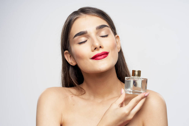 Retrato de mujer joven y hermosa con frasco de perfume aislado sobre fondo blanco
 - Foto, Imagen