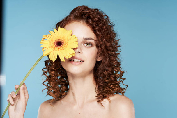Νεαρή γυναίκα με λουλούδι που ποζάρει στο στούντιο - Φωτογραφία, εικόνα