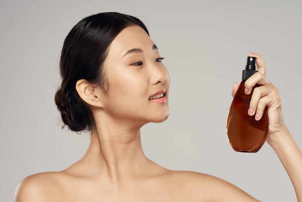 Young asian woman with hair spray in studio. Beauty, fashion photography - Photo, Image