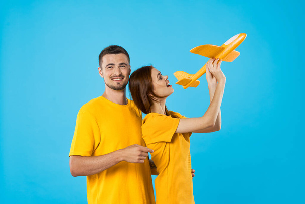 Jeune beau couple jouant avec avion jouet jaune sur fond bleu  - Photo, image