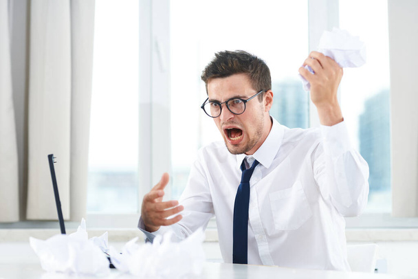 Young aggressive  businessman in the office  with documents  - 写真・画像