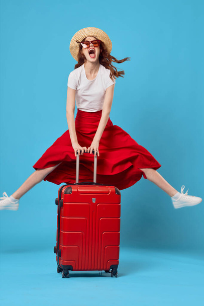 Νεαρή γυναίκα με κόκκινη βαλίτσα στο στούντιο - Φωτογραφία, εικόνα
