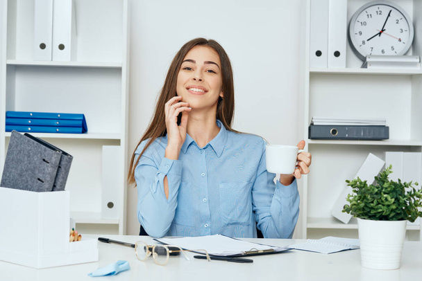 junge schöne Geschäftsfrau sitzt am Schreibtisch im Büro mit Kaffee - Foto, Bild