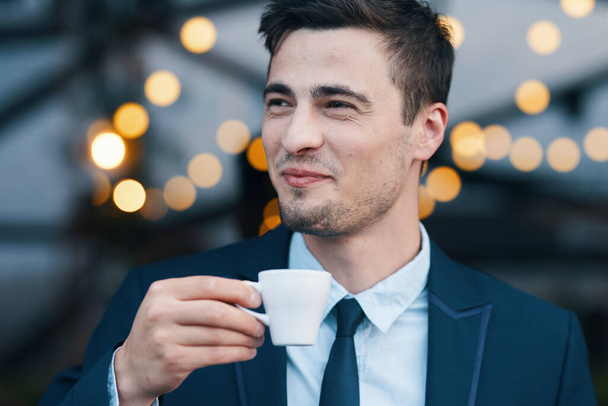 Junger gutaussehender Geschäftsmann im Café mit Tasse Kaffee - Foto, Bild