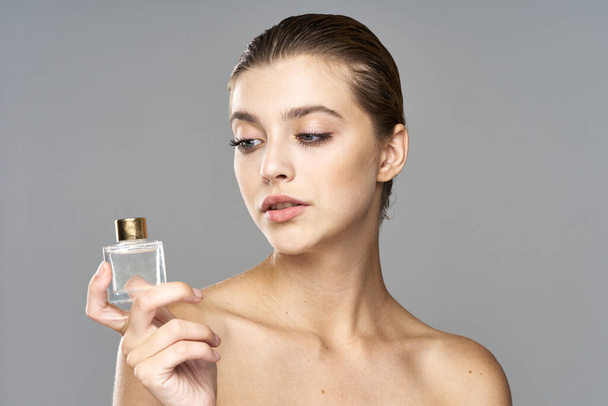 Fiatal, gyönyörű nő parfümös üveggel a kezében. Stúdió felvétel  - Fotó, kép