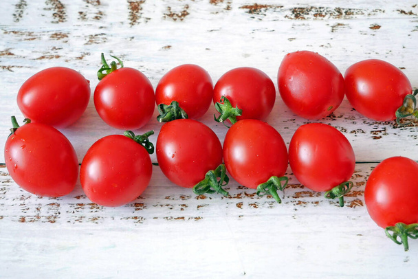svěží červené lahodné rajčata třešeň v surovém tvaru na dřevěném pozadí - Fotografie, Obrázek