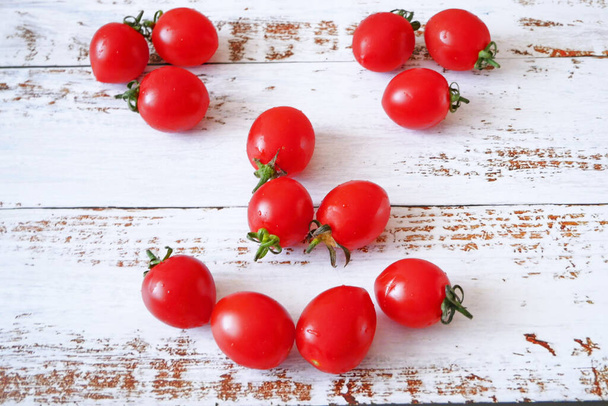 fresh red delicious tomatoes cherry in the smile face shape on white wooden background - Fotó, kép