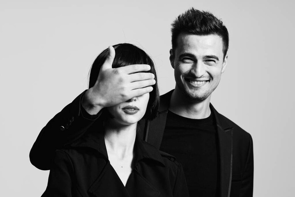Young beautiful couple  in studio. Man closing woman's eyes.  Black and white.    - Foto, immagini
