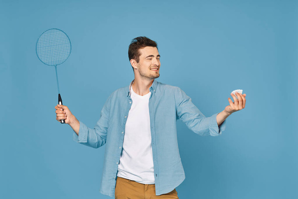Young man playing tennis isolated on blue background, studio shot - Photo, Image