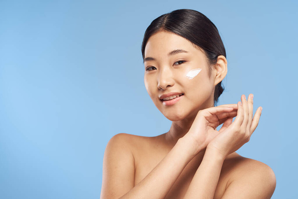 ritratto di bella donna asiatica applicazione crema su sfondo isolato - Foto, immagini
