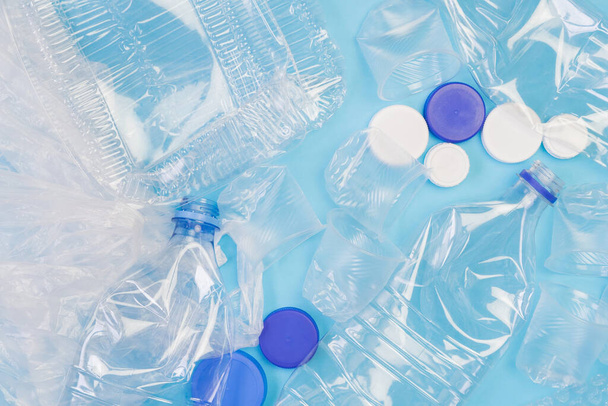 Διαφορετικά πλαστικά σκουπίδια σε μπλε φόντο. Έννοια ανακύκλωσης πλαστικών αποβλήτων. Οικολογία και περιβαλλοντική φροντίδα. Πάνω όψη επίπεδη lay. - Φωτογραφία, εικόνα