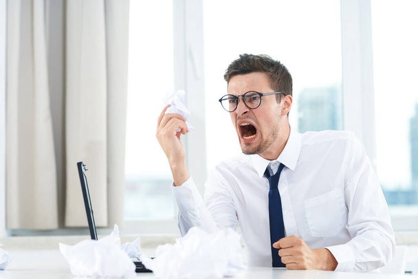 Młody wściekły krzyczący biznesmen w biurze z dokumentami - Zdjęcie, obraz