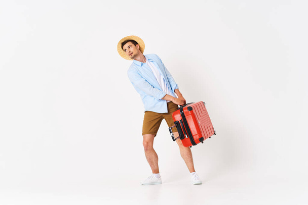 Young man with red suitcase in studio - Fotó, kép