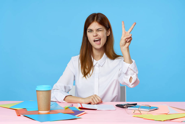 молода красива бізнес-леді сидить за столом в офісі з жестом
  - Фото, зображення