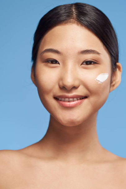 Young asian woman applying moisturizer on her face  - Foto, afbeelding