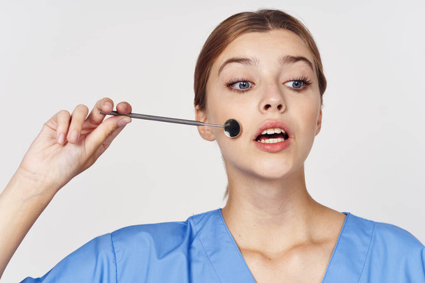 junge Krankenschwester mit Zahnspiegel Werkzeug. Studioaufnahme - Foto, Bild