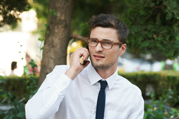 Fiatal jóképű üzletember telefonnal a kávézóban  - Fotó, kép