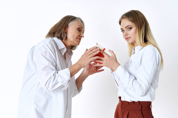senior and young women with gift in studio     - Photo, Image