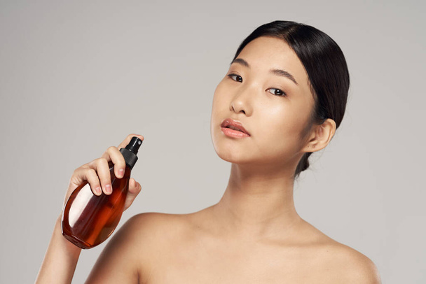 Young asian woman with hair spray in studio. Beauty, fashion photography - 写真・画像