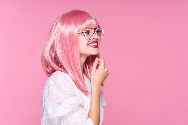 Νεαρή γυναίκα με ροζ περούκα και γυαλιά σε ροζ φόντο - Φωτογραφία, εικόνα