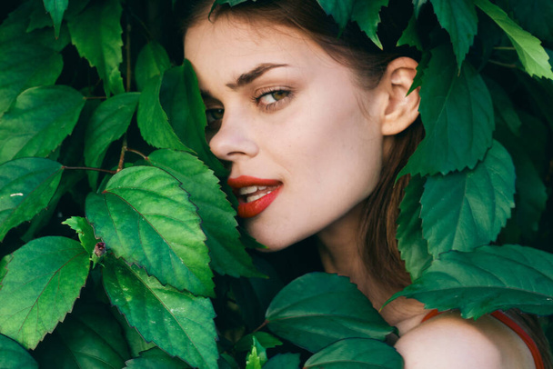Young beautiful woman posing with leaves around her face - Foto, imagen