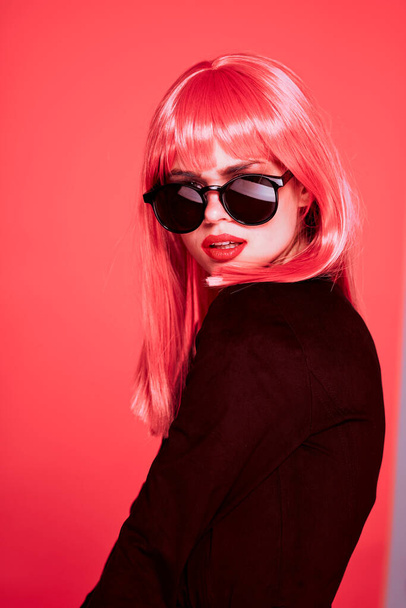 молода красива жінка в рожевій перуці і сонцезахисних окулярах позує в студії
  - Фото, зображення