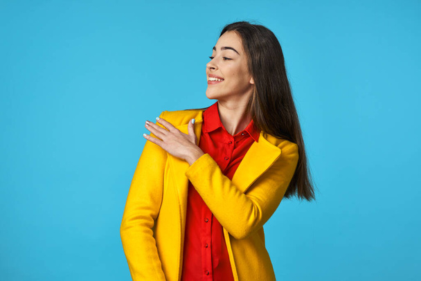 young beautiful woman in yellow jacket  looking away   in Studio with blue Background. - Photo, Image