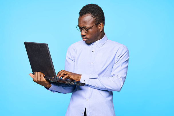 Mladý africký podnikatel držící notebook izolované na modrém pozadí - Fotografie, Obrázek