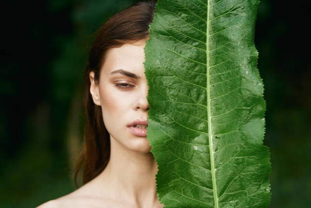 Giovane bella donna in posa con foglia verde in giardino - Foto, immagini