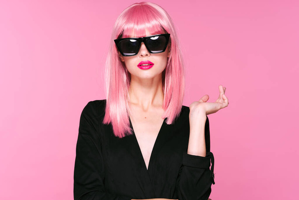 fiatal gyönyörű nő rózsaszín paróka és napszemüveg pózol stúdióban  - Fotó, kép