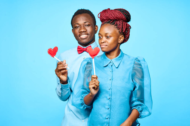 junges schönes Paar mit roten Herzen posiert im Studio auf blauem Hintergrund - Foto, Bild