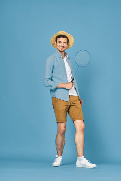 Young man playing tennis isolated on blue background, studio shot - Foto, Bild