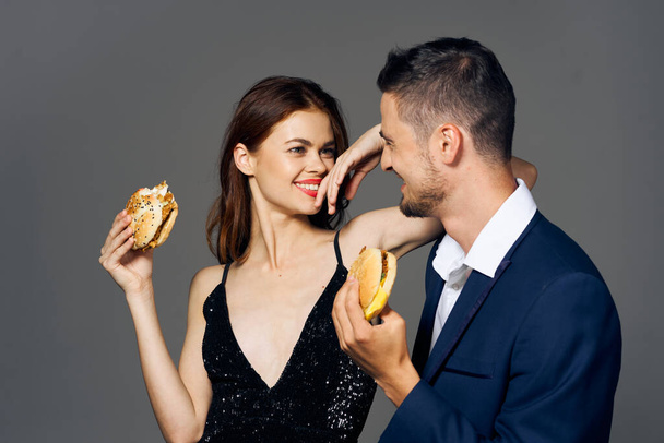 若い美しいカップルがハンバーガーを食べている。スタジオショット - 写真・画像