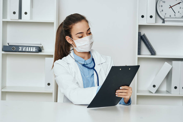 Giovane medico che prende appunti mentre è seduto alla scrivania in ospedale  - Foto, immagini