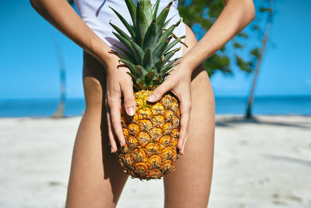 A woman in a white swimsuit with pineapple.  High quality photo - Фото, изображение