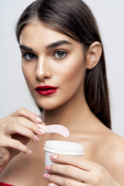Studio shot of young beautiful woman with cream, beauty product on an isolated background - Foto, afbeelding